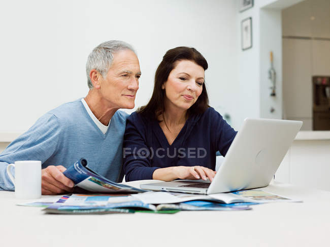Mature couple using laptop to booking vacation — Stock Photo