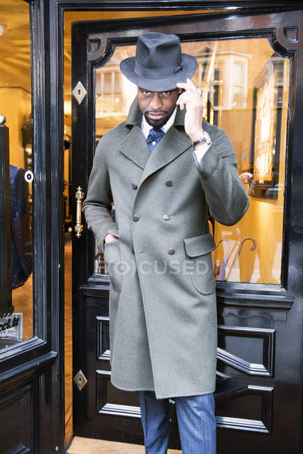 Cliente masculino em casaco e trilby fora alfaiates loja — Fotografia de Stock