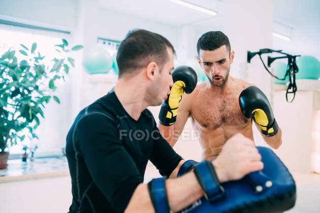 Hombre entrenamiento de kickboxing con entrenador personal en el gimnasio - foto de stock