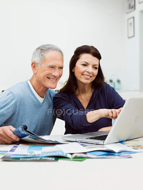 Зрелая пара, использующая ноутбук для бронирования отдыха — стоковое фото