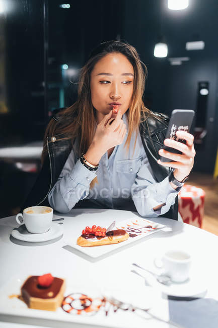 Donna in ristorante mangiare dessert e utilizzando smartphone — Foto stock