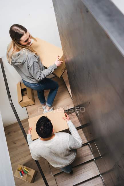 Couple carrying cardboard boxes upstairs — Stock Photo