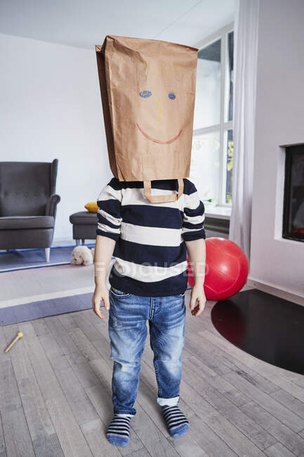 Portrait of young boy with brown bag on head, drawn face on brown bag — Stock Photo