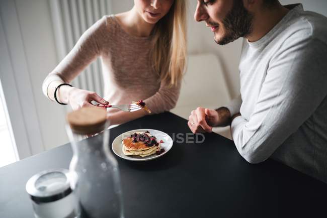 Обрезанный вид пары, поедающей блинчики — стоковое фото