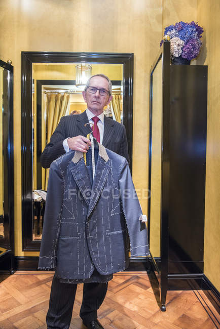 Tailleur tenant veste sur mesure inachevée dans le magasin de tailleur — Photo de stock