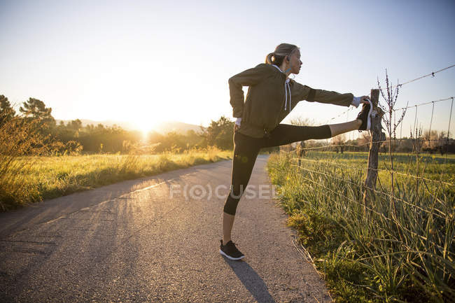 Mujer joven que ejerce en un entorno rural - foto de stock