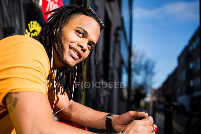 Портрет молодого человека с наушниками, улыбающегося на улице — стоковое фото