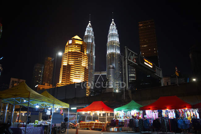 Kampung baru market by petronas towers illuminated at night, Kuala Lumpur, Malasia - foto de stock