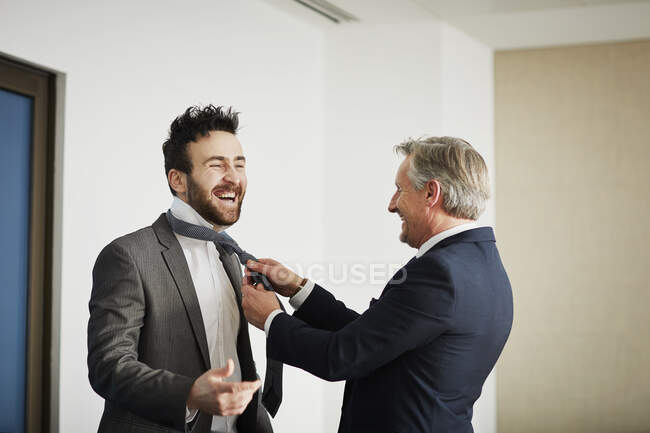 Старший бізнесмен закріплює краватку колеги в офісі — стокове фото