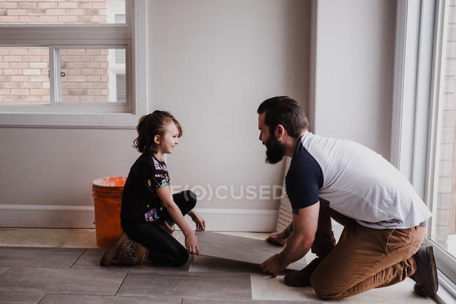 Fille aider père installation carreaux de sol — Photo de stock