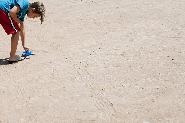 Мальчик играет с игрушечным самолетом на полу — стоковое фото