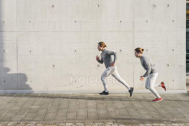 Молоді близнюки-чоловіки біжать разом — стокове фото