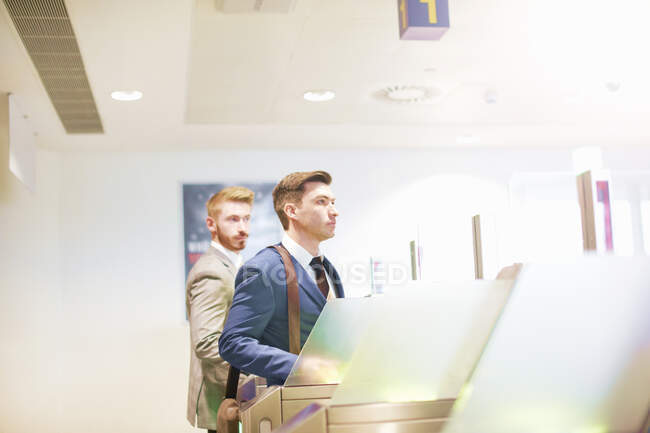 Dos hombres caminando por la puerta de seguridad en el aeropuerto, vista lateral - foto de stock