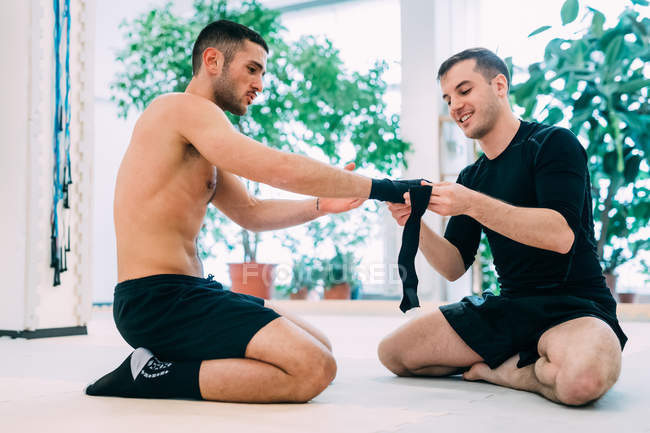 Coach wrapping boxer hands on floor — Stock Photo