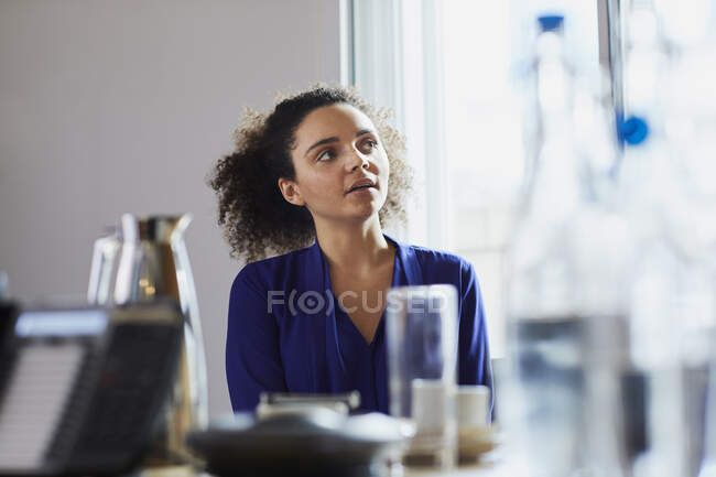 Молода бізнес-леді слухає за столиком на дошці — стокове фото