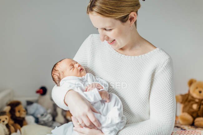 Mother holding newborn baby girl, smiling — Stock Photo