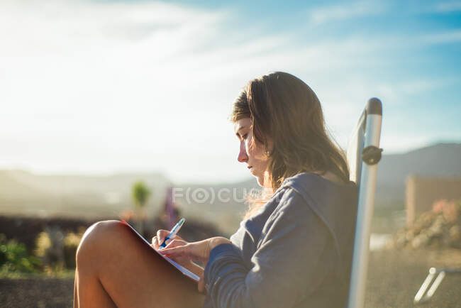 Mulher em cadeira de praia escrevendo em diário, Corralejo, Fuerteventura, Ilhas Canárias — Fotografia de Stock