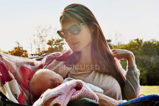 Mujer acunando bebé hija en el jardín - foto de stock