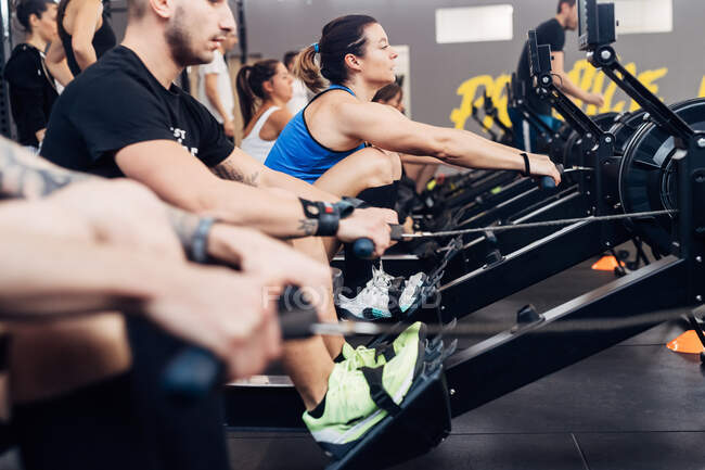 Large group of people using rowing machine in gym — Stock Photo