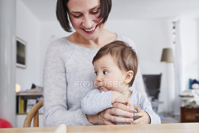 Portrait of woman sitting at table with baby daughter — Stock Photo