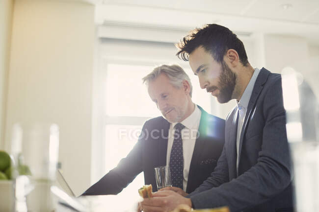Empresarios mirando el portátil durante el almuerzo de trabajo - foto de stock