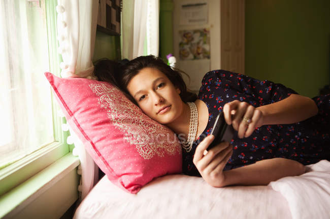 Adolescente couchée sur le lit avec smartphone — Photo de stock