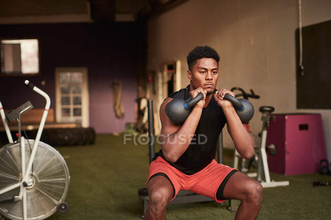 Homme dans la salle de gym utilisant des cloches de bouilloire — Photo de stock