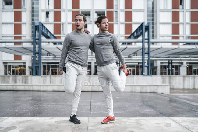 Молоді чоловіки близнюки тренуються і розтягуються разом — стокове фото