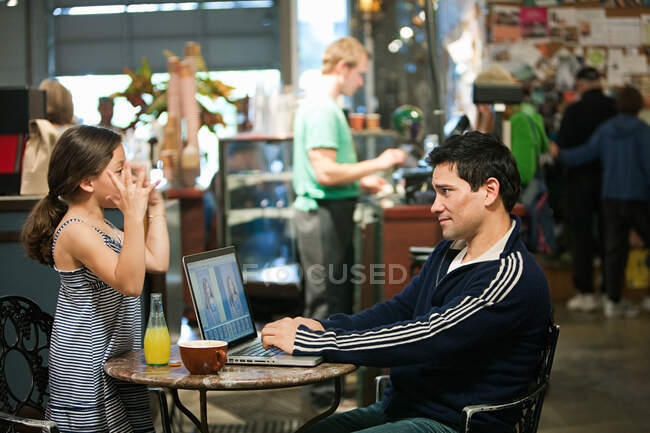 Отец и дочь с ноутбуком в кафе — стоковое фото