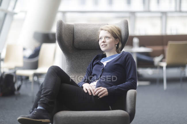 Frau macht Pause und sitzt im Sessel im Büro — Stockfoto