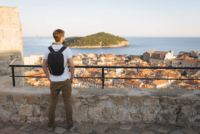 Rückansicht eines Mannes, der über Dächer hinweg aufs Meer blickt, dubrovnik, dubrovacko-neretvanska, Kroatien, Europa — Stockfoto