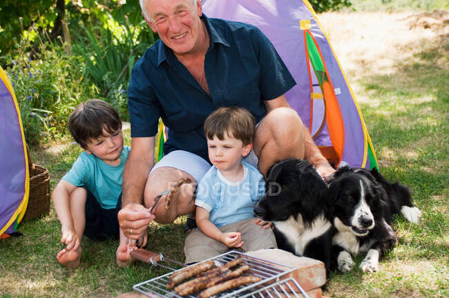 Abuelo y nietos haciendo barbacoa - foto de stock