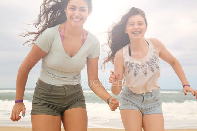 Portrait of two teenage girls on beach, smiling — Stock Photo