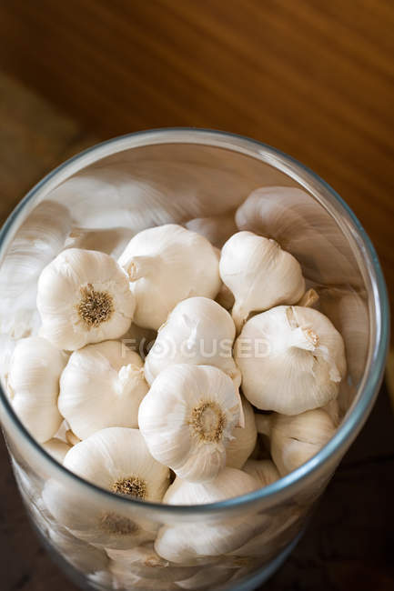 Elevated view of garlic bulbs in glass container — Stock Photo