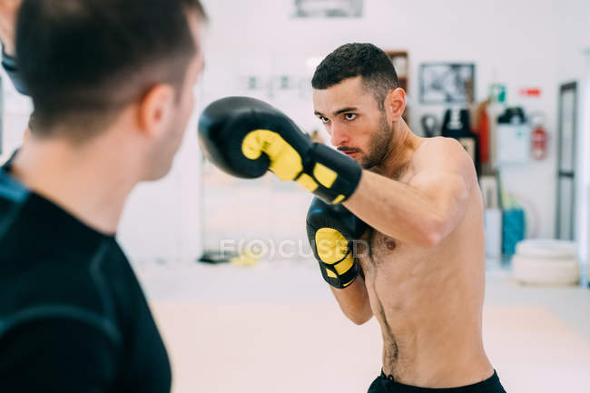 Man wearing in boxing gloves sparring with personal trainer — Stock Photo