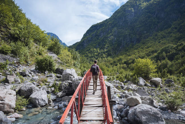 Rear view of man crossing bridge in Accursed mountains, Theth, Shkoder, Albania, Europe — Stock Photo
