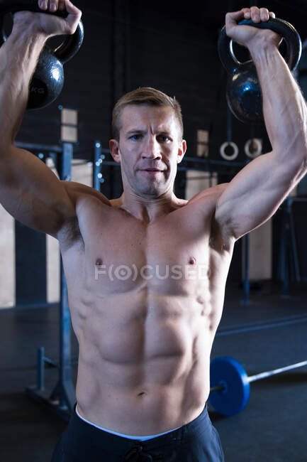 Мужчина тренируется в спортзале, поднимает гири — стоковое фото