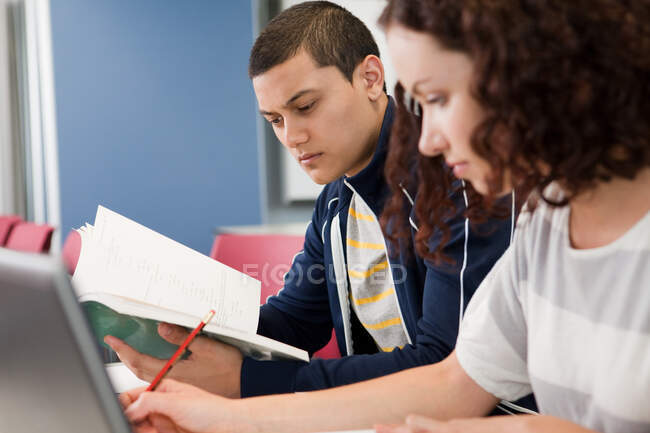 Estudiante universitario estudiando libro de texto en clase - foto de stock