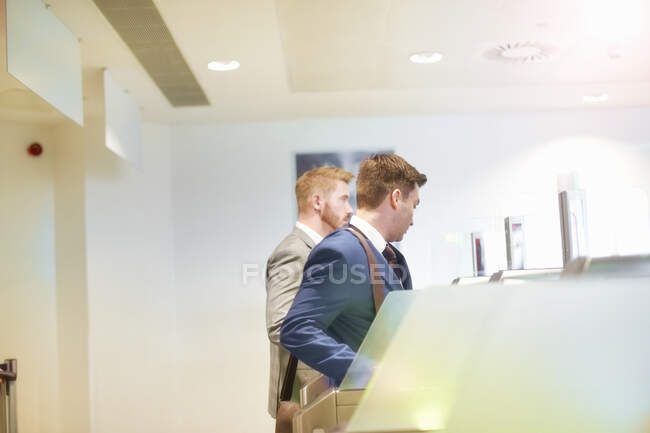 Two men walking through security gate at airport, side view — Stock Photo