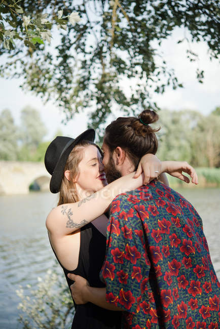 Jovem casal abraçando e beijando por lago, Toscana, Itália — Fotografia de Stock