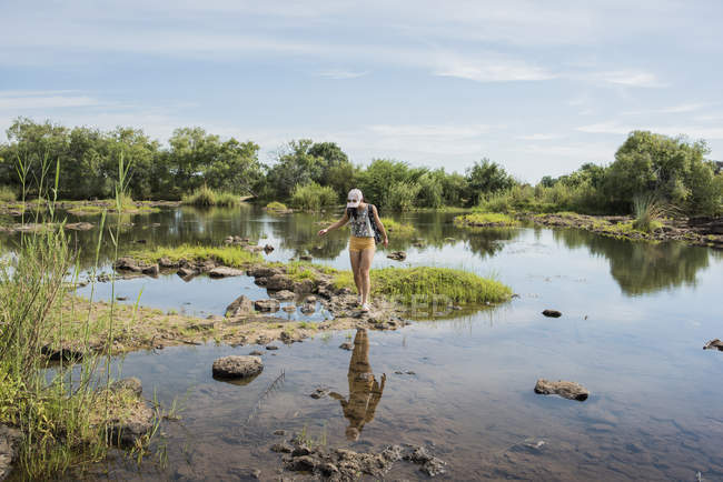 Distant side view of Young female tourist looking out over calm waters near Victoria Falls, Zimbabwe, Africa — Stock Photo