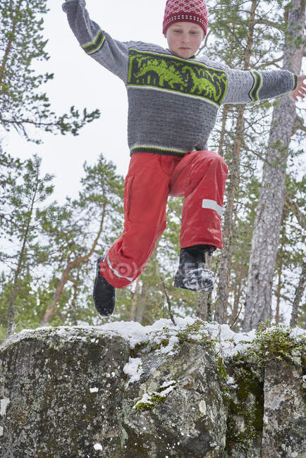 Junger Junge springt von Felsvorsprung, in ländlicher Landschaft, Blick aus dem niedrigen Winkel — Stockfoto