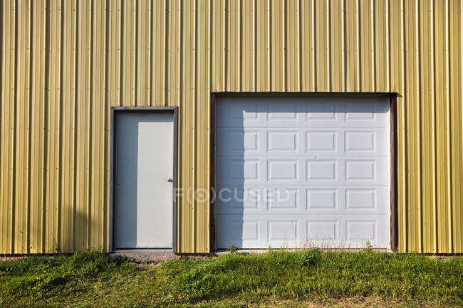 Porta bianca e porta garage in edificio con parete gialla — Foto stock