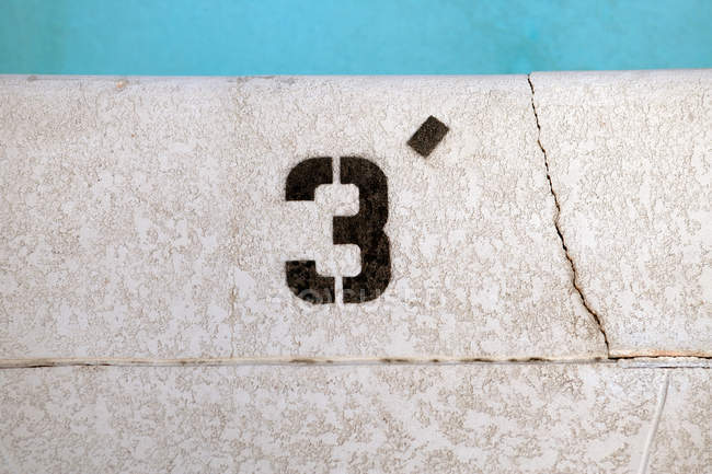 Junto a la piscina con el número 3 en el borde, vista de primer plano - foto de stock