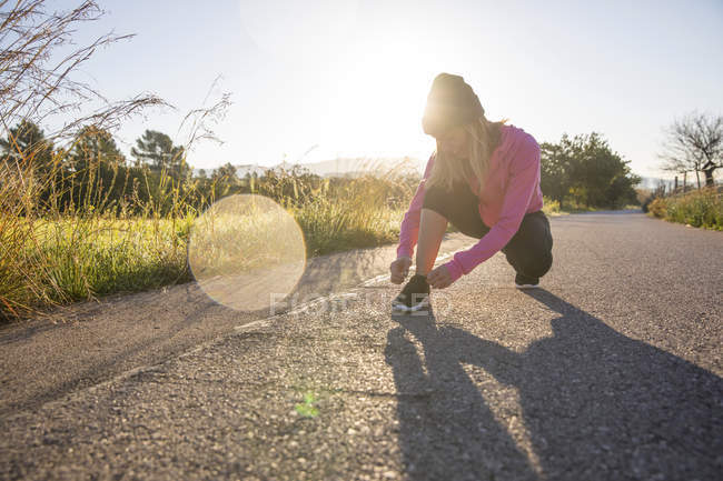 Молодая женщина завязывая шнурки для занятий на открытом воздухе — стоковое фото