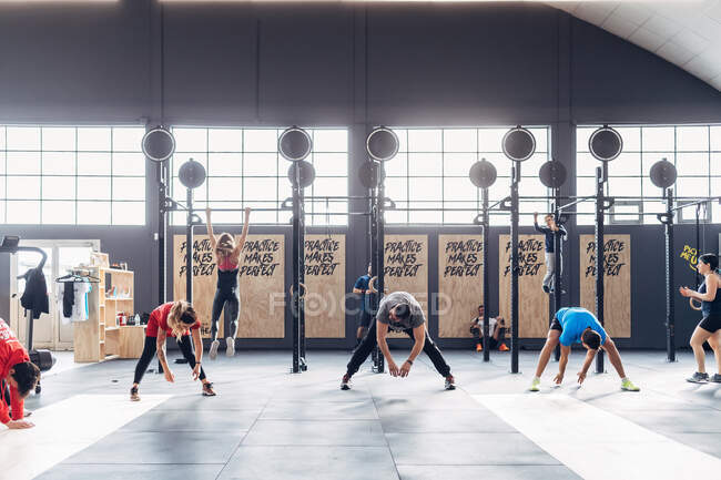 Group of people exercising in gym, bending forwards — Stock Photo