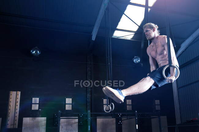 Мужчина в спортзале, балансирует на гимнастических кольцах — стоковое фото