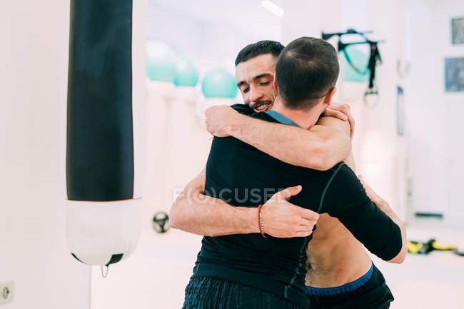 Amigos varones abrazándose en el gimnasio - foto de stock
