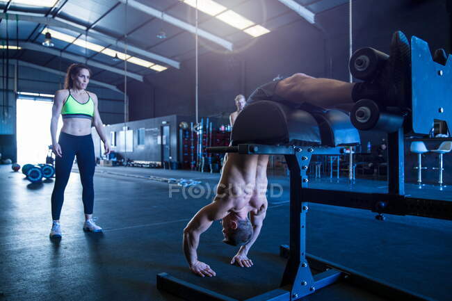 Três pessoas se exercitando no ginásio, usando equipamentos — Fotografia de Stock