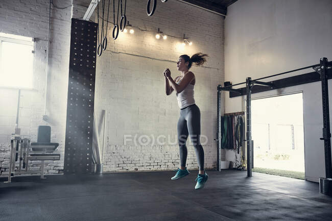 Женщина в спортзале прыгает в воздухе — стоковое фото